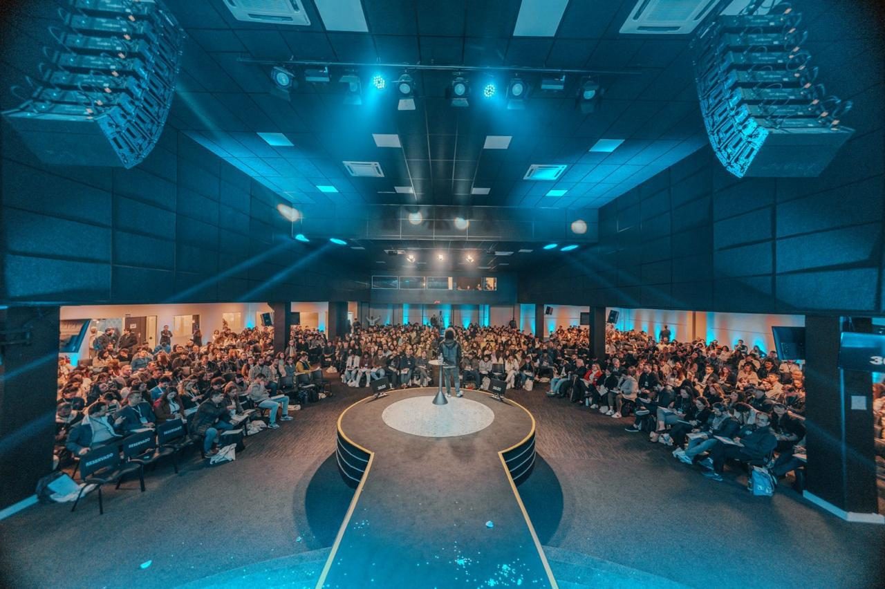 Auditório lotado visto do palco, iluminado em azul, na Imersão Euriliano de agosto de 2025