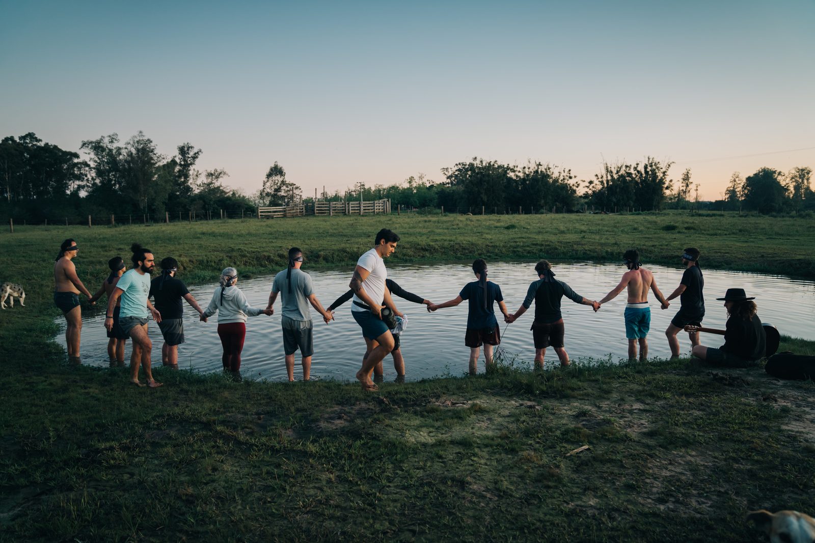 Grupo da Imersão do Mato de mãos dadas dentro de um lago ao pôr do sol